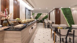 Un hall d’hôtel moderne doté d’un espace buffet, d’un coin salon et d’un mur végétal vertical.