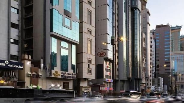 Une rue moderne, située en milieu urbain, bordée d’immeubles imposants, dont un bâtiment remarquable surmonté d’une statue.