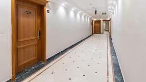 Un couloir d’hôtel avec des portes en bois, un sol carrelé et un long passage.