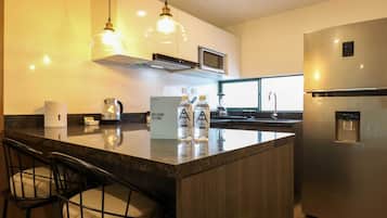 A modern kitchen with a central island, stainless steel appliances, and bar seating.