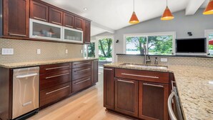 A modern kitchen with dark wood cabinets, a granite countertop, and a built-in dishwasher.