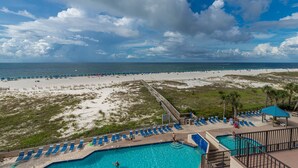 A beach resort with a swimming pool, beach chairs, and a view of the ocean. - Beach Front 2 Bedroom Condo - Phoenix East 407 (Orange Beach)