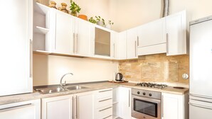 Une cuisine moderne avec des meubles blancs, un évier en acier inoxydable, un réfrigérateur Bosch et une cuisinière à gaz.