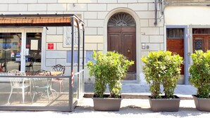 Un bâtiment dont la devanture est fermée, avec une porte en bois et des plantes en pot devant l’entrée.