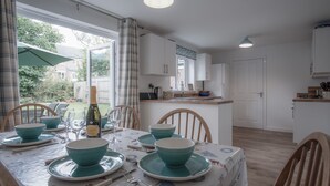 Een eetruimte met een tafel voor vier personen, stoelen en uitzicht op de achtertuin.