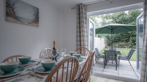Een eetruimte met een tafel voor vier personen, stoelen, een fles champagne en een groene paraplu.
