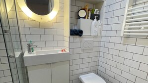 Ein kleines Badezimmer mit einem weißen Waschbecken, einer Toilette und einem Ablagefach für Pflegeprodukte.
