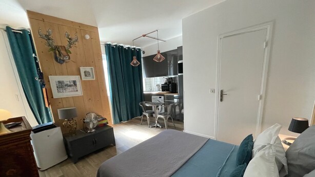 Ein Schlafzimmer mit Bett, Schreibtisch und einer kleinen Küche im Hintergrund.