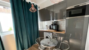 Eine kompakte Küche mit Waschmaschine, Mikrowelle und Kaffeemaschine auf der Arbeitsplatte.