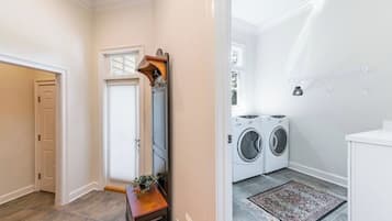 A laundry room with a washing machine and dryer, a wooden bench, and a rug.