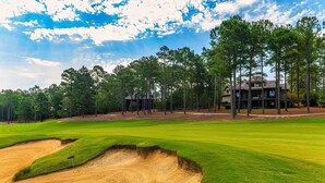 Un campo de golf con búnkeres, árboles y un club de campo.