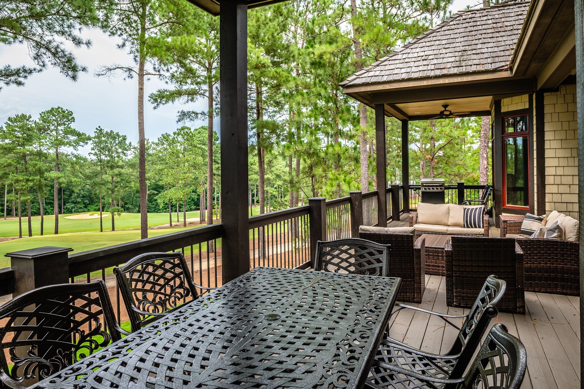 A covered outdoor area with a table and chairs, a sofa, and a grill.