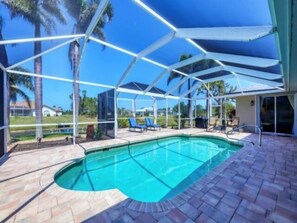A covered outdoor swimming pool with lounge chairs and a patio area. - Beautiful Canal front home in Rotonda West (Rotonda West)