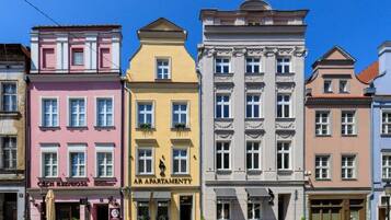 A row of colorful buildings with distinct architectural styles, including a pink building with a sign that reads "Czech Rzeszow" and a yellow building with a sign that reads "AR APARTMENTY".