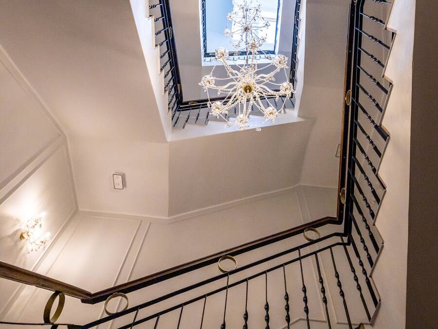 Een moderne trap met een dakraam, een kroonluchter en een decoratieve plafondlamp.