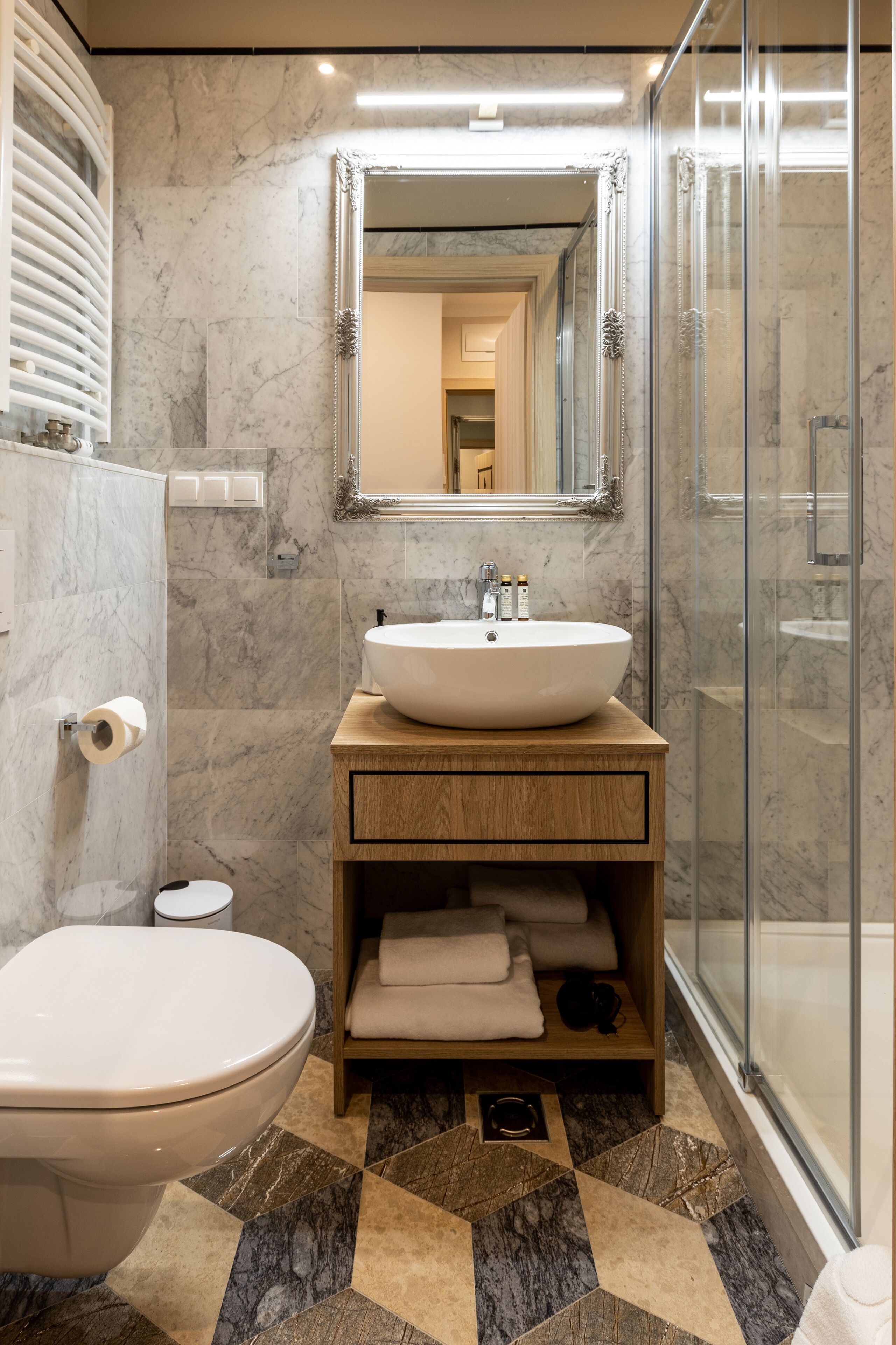 Une salle de bain moderne avec un sol en marbre, un grand lavabo, un miroir et un espace douche.