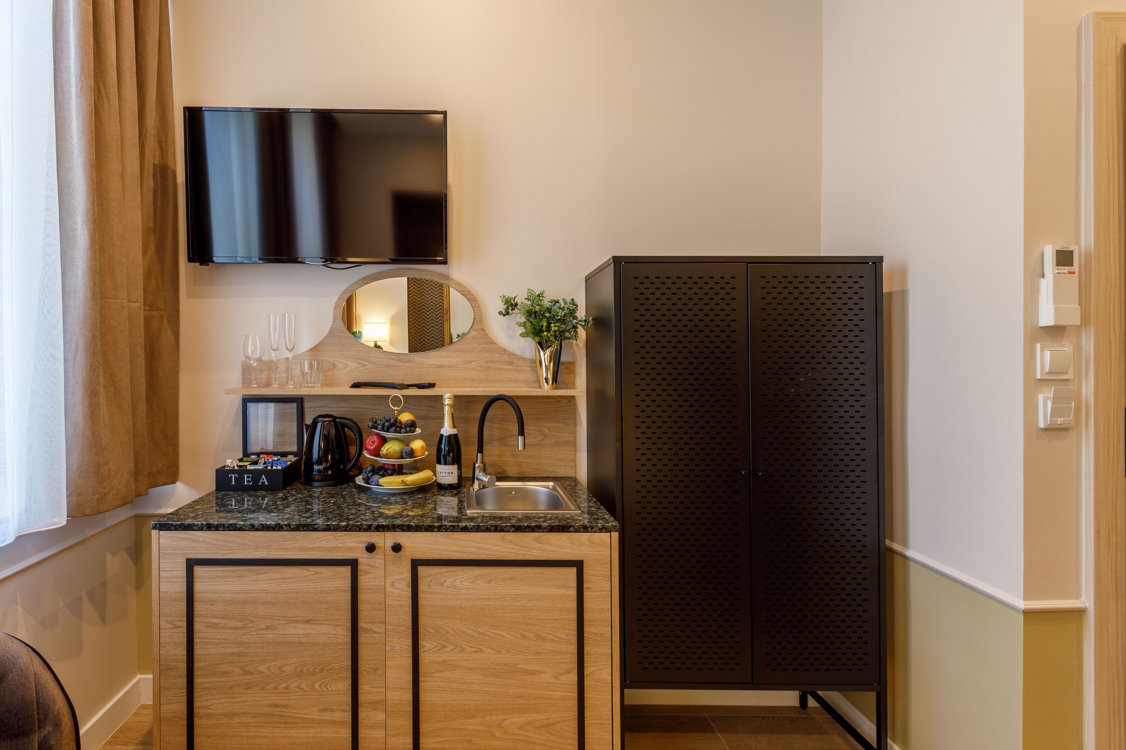 A compact kitchen with a flat-screen TV, a sink, and a small refrigerator.