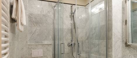 A modern bathroom with a glass-enclosed shower, a toilet, and a sink.