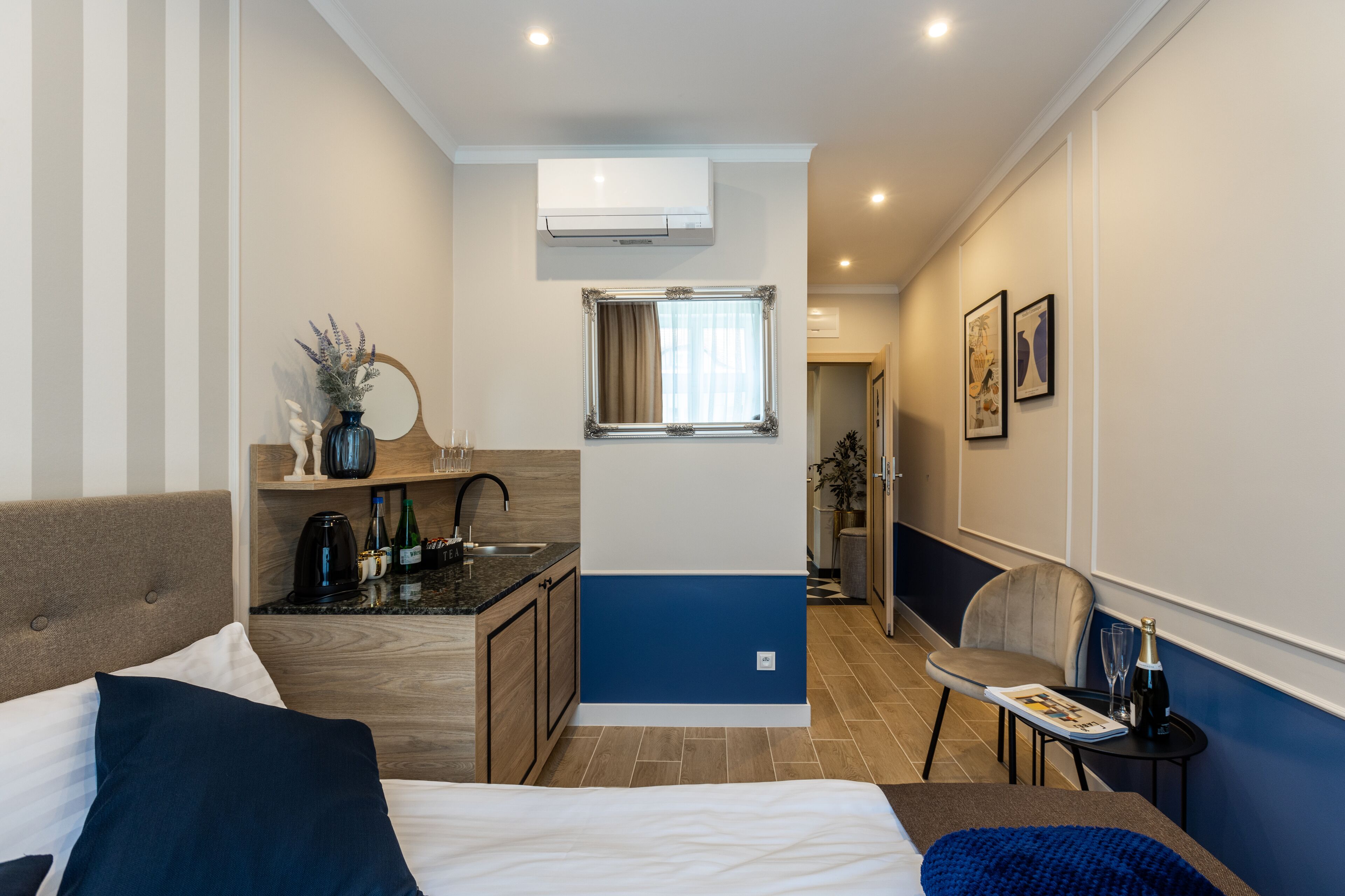 Een compacte hotelkamer met een bed, een kitchenette, een raam en een zithoek.