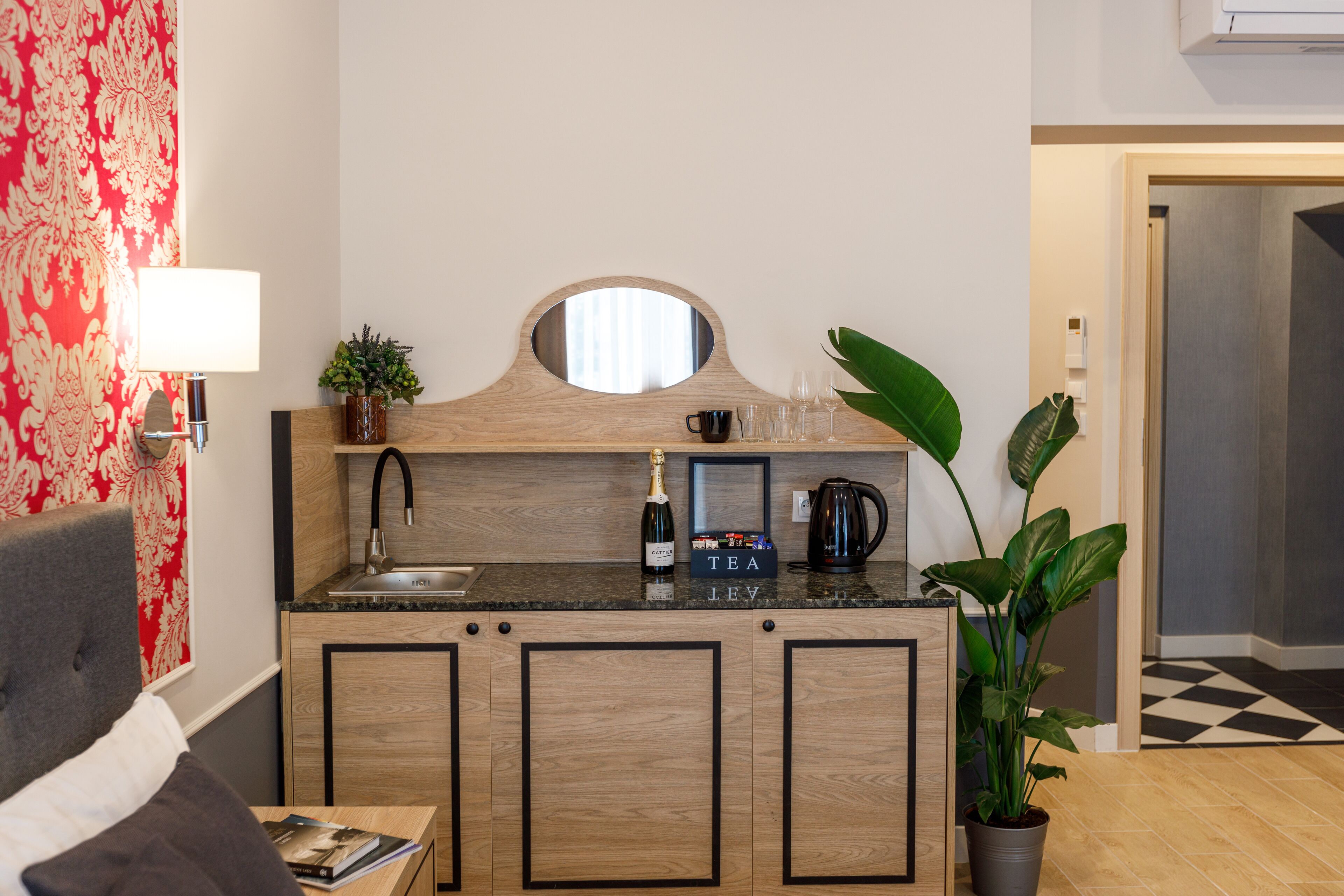 A compact kitchen with a wooden countertop, a sink, a mirror, and a potted plant.