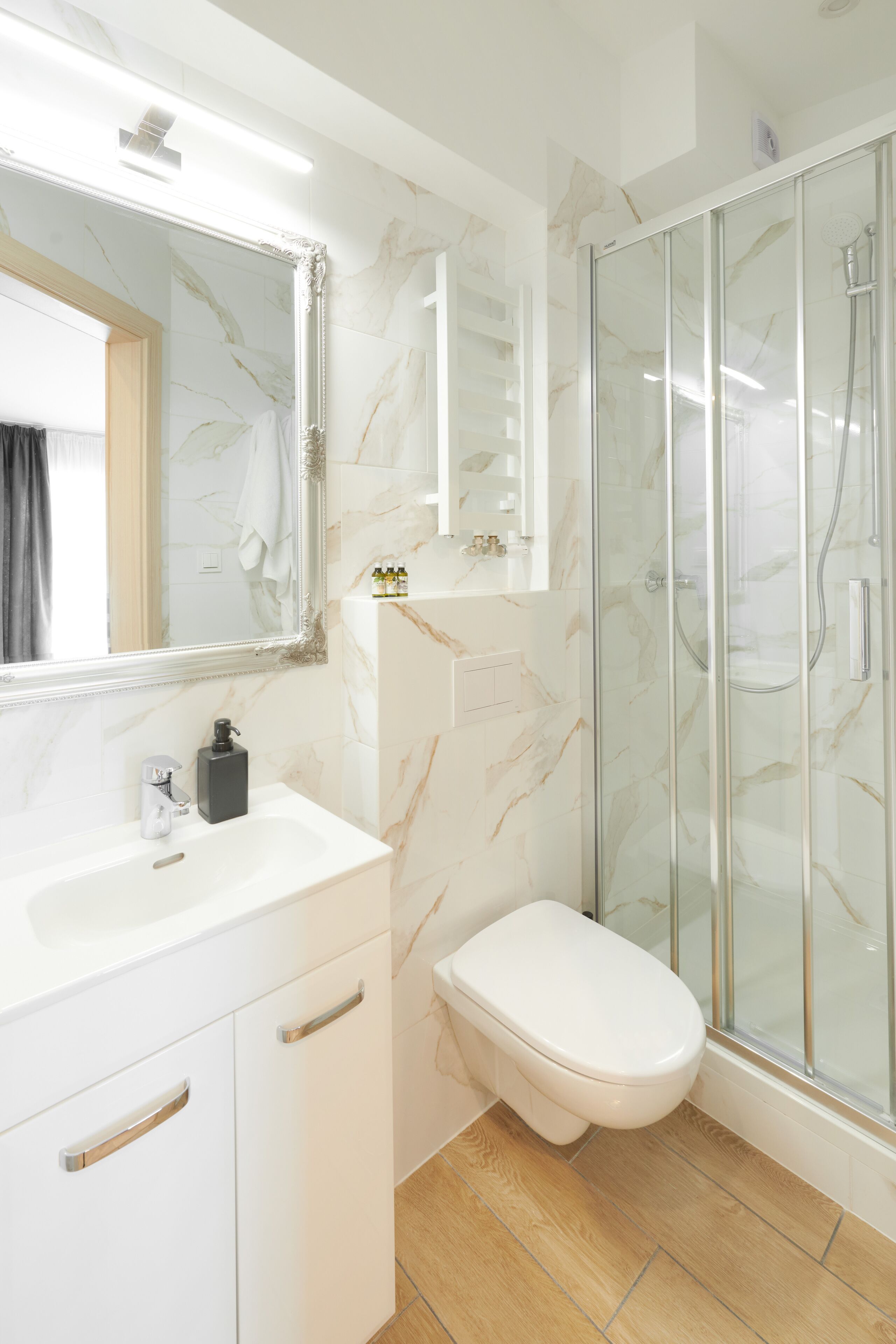 Un baño moderno con lavamanos de mármol, inodoro y ducha con cerramiento de vidrio.