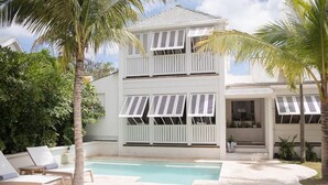 A two-story building with a pool, surrounded by palm trees and a well-maintained garden.