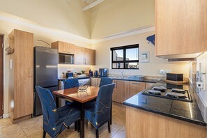 Une cuisine moderne avec des meubles en bois, un réfrigérateur en acier inoxydable, un four à micro-ondes et une cuisinière à gaz.
