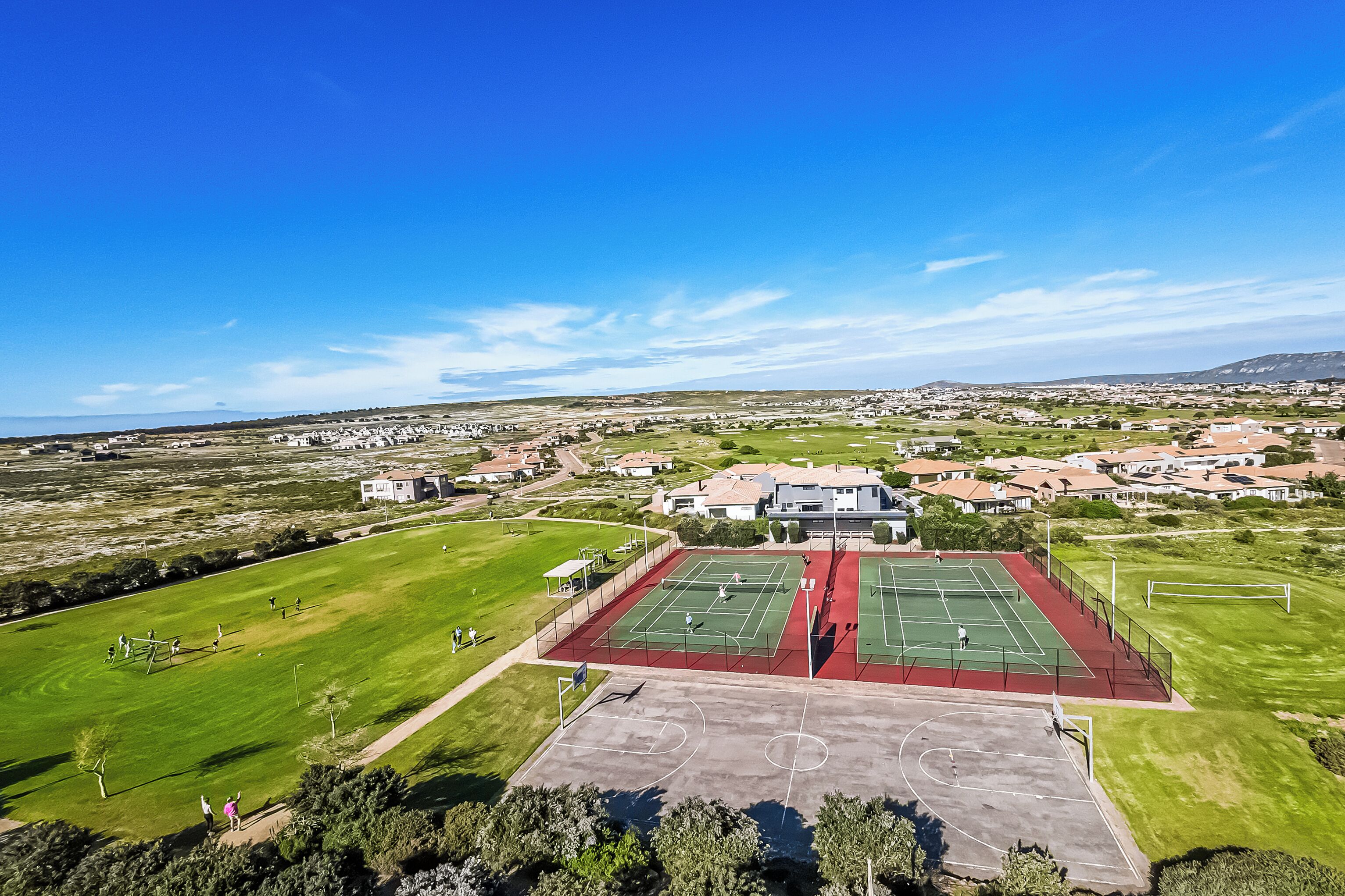 Zona residencial con una gran cancha de tenis y una cancha de baloncesto más pequeña.