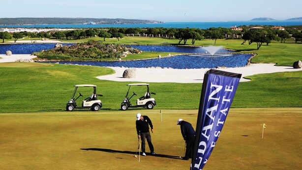 En golfbane med et vandhazard, et flag og en golfbil.