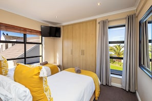 Une chambre d’hôtel avec deux lits, une télévision, une armoire et un balcon avec vue.