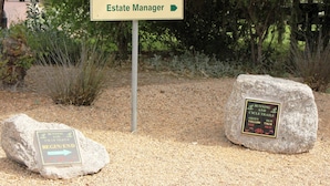 Skilt med 'Estate Manager', pile der angiver vej og to informationsskilte på sten.