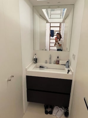 Bathroom features a vanity with sink, faucet, and mirror, along with a cabinet and towel holder.
