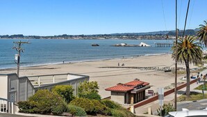 Une vue côtière avec une plage, une jetée et un bâtiment doté d’un toit rouge.