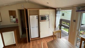 Une cuisine compacte équipée d’un réfrigérateur, d’un four à micro-ondes et d’un coin repas avec une table et des chaises.