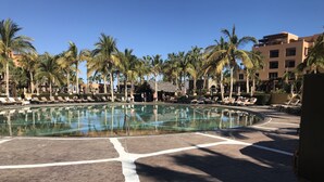 Zona de piscina amb gandules i palmeres.