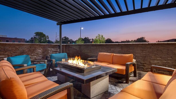 An outdoor patio with a fire pit, wicker furniture, and a stone wall backdrop. - Hyatt House Mall Of America Msp Airport (Bloomington)
