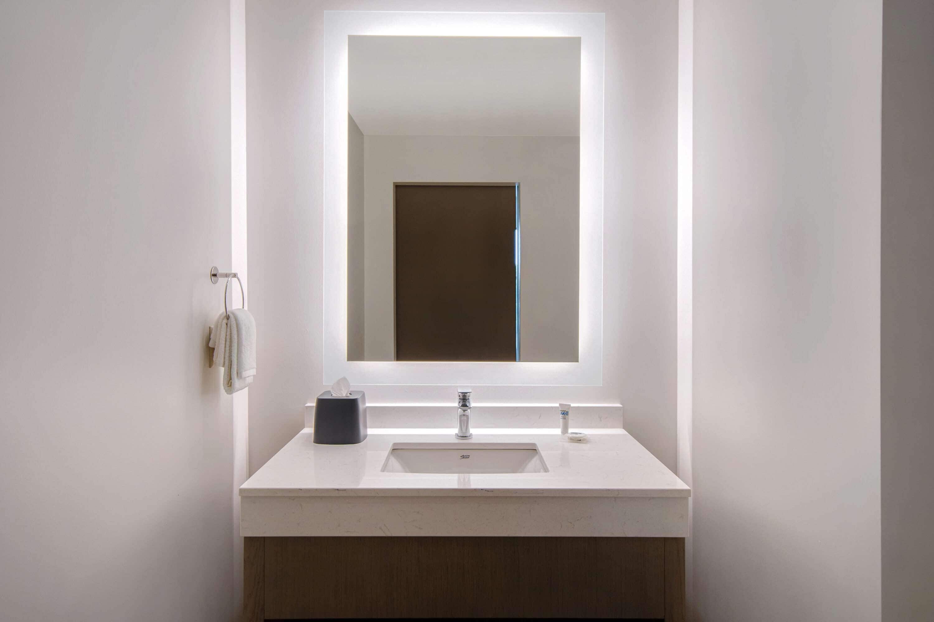 A modern bathroom with a white sink, a mirror, and a towel rack.