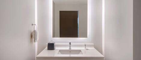A modern bathroom with a white sink, a mirror, and a towel rack.