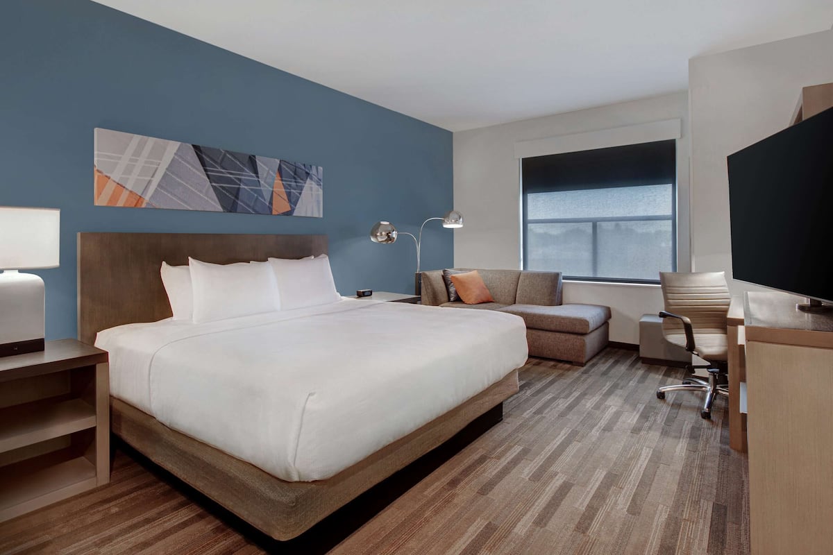 Une chambre d’hôtel avec un grand lit, un bureau, une chaise, une télévision et une fenêtre.