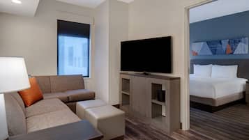 A modern hotel room with a sofa, TV, and a bed.
