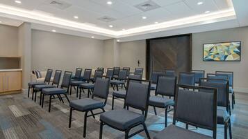 A conference room with rows of chairs, a carpeted floor, and a large door.