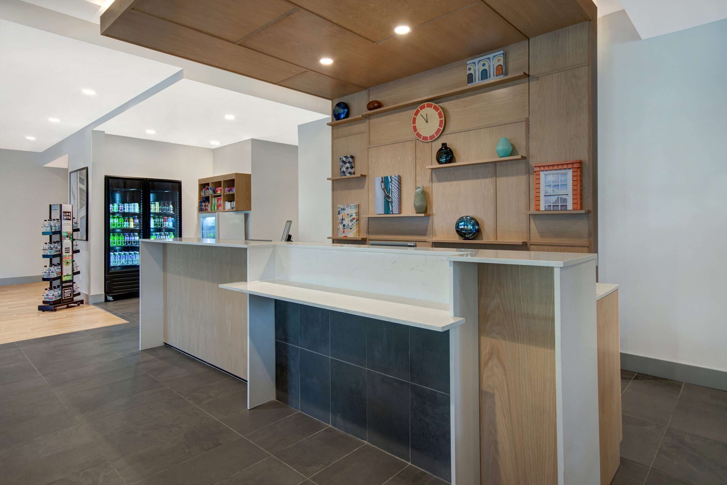 A reception area with a wooden reception desk, a clock, and shelves with decorative items.