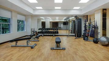 A gym with exercise equipment, a bench, dumbbells, and a large mirror.