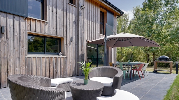 Un área de estar al aire libre moderna con muebles de mimbre y un paraguas grande.