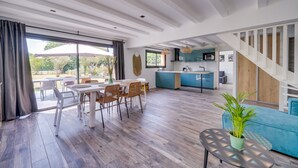 Amplia sala de estar con mesa de comedor, sillas, sofá y una planta en maceta.