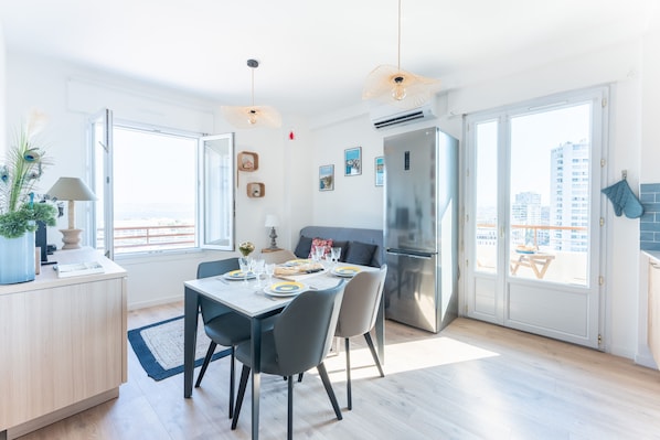 A modern kitchen with a dining area, large windows, and a view of the city.