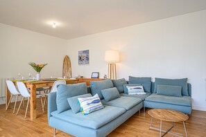 Un salon moderne avec un canapé bleu, une table à manger en bois et une lampe.