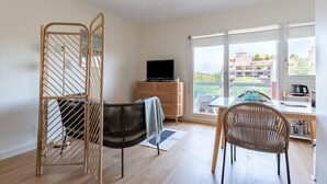 A modern living room with a sofa, a dining table, and a TV. - LE NID DES CEDRES - Magnifique Studio terrasse Montplaisir (Lyon)