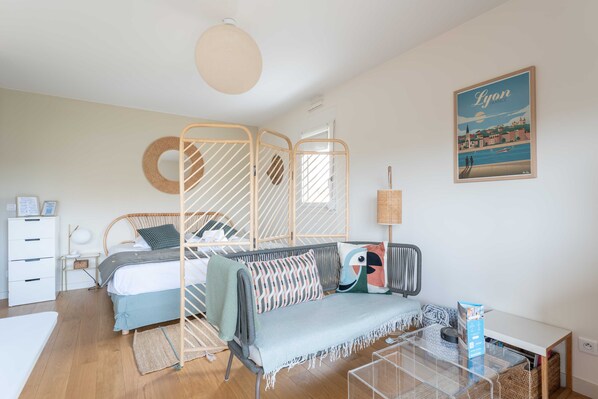 A well-lit room with a bed, a sofa, a coffee table, and a wall-mounted lamp.