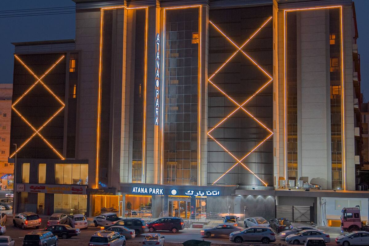 A modern building with ATANA PARK signage, featuring vertical light strips and a prominent entrance.